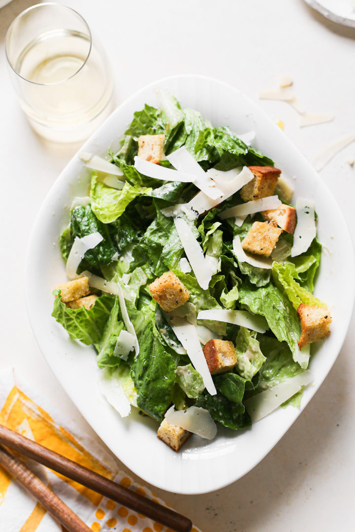 homemade caesar salad in a white salad bowl