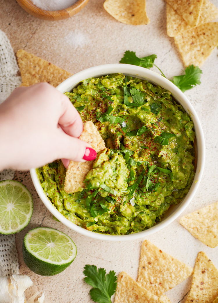 woman dipping a chip in a bowl of guacamole