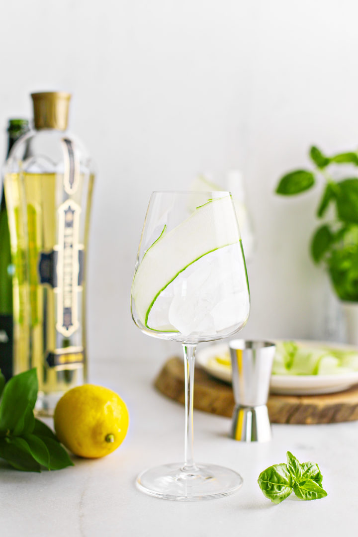step photo showing how to add a cucumber ribbon garnish to a st germain spritz
