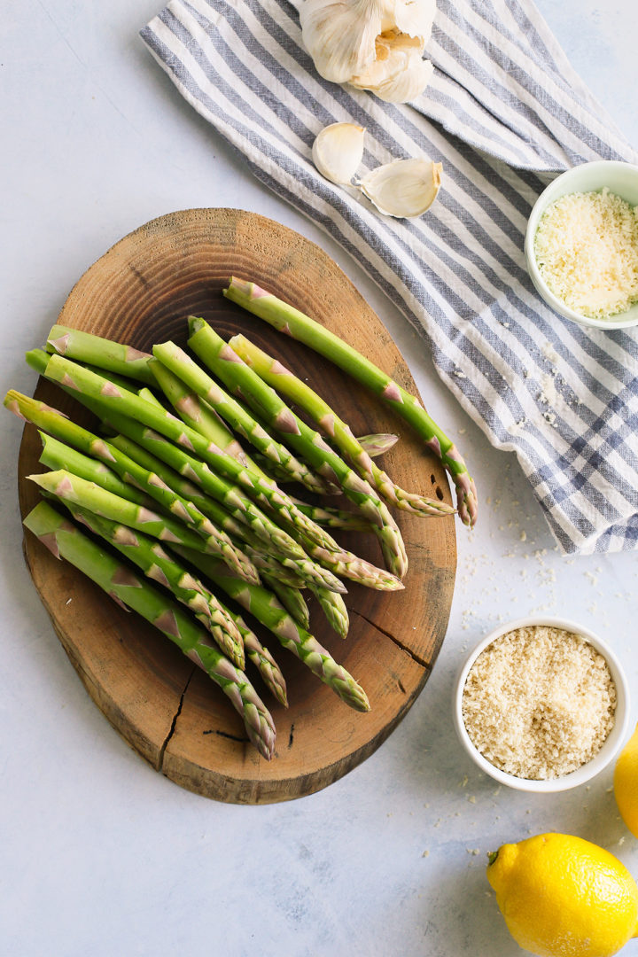 overhead photo of fresh asparagus, breadcrumbs, garlic, parmesan, and lemons to make pellet grilled asparagus