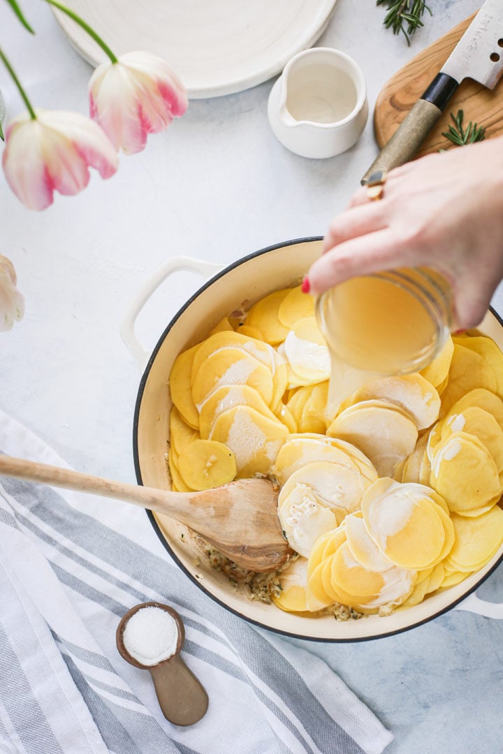 adding chicken broth to scalloped potatoes