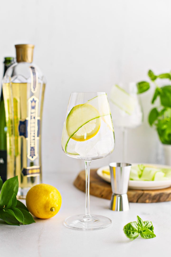 step photo showing how to add a fresh lemon slice garnish to a elderflower spritz recipe