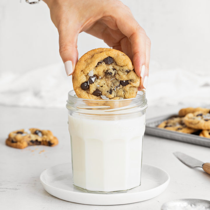 woman dipping a chocolate chip cookie into a glass of milk