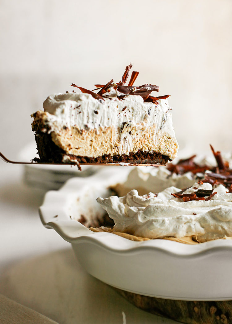 peanut butter pie with chocolate graham cracker crust in a white pie plate being served with a pie server