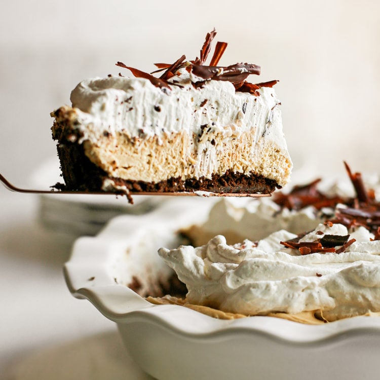 peanut butter pie with chocolate graham cracker crust in a white pie plate being served with a pie server