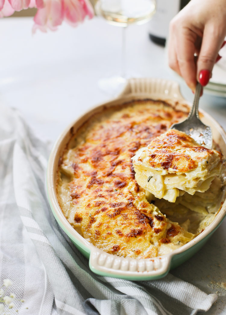 woman serving scalloped potatoes from a baking dish