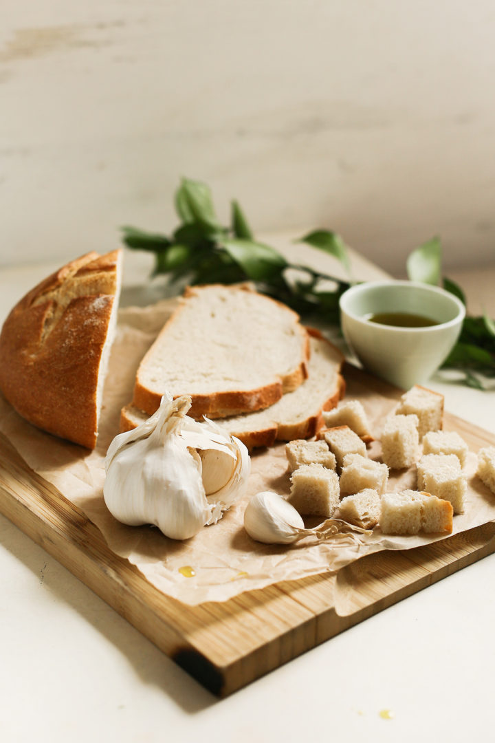 sourdough bread cubes with garlic and olive oil on a wooden cutting board to use for sourdough croutons