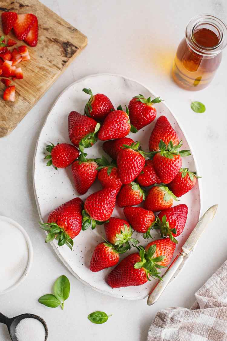 a white platter with fresh strawberries