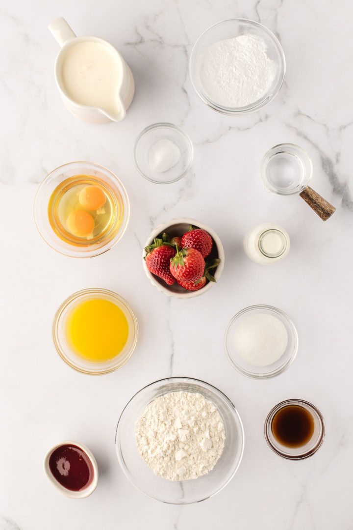 overhead photo a marble counter with bowls filled ingredients to make strawberry crepes