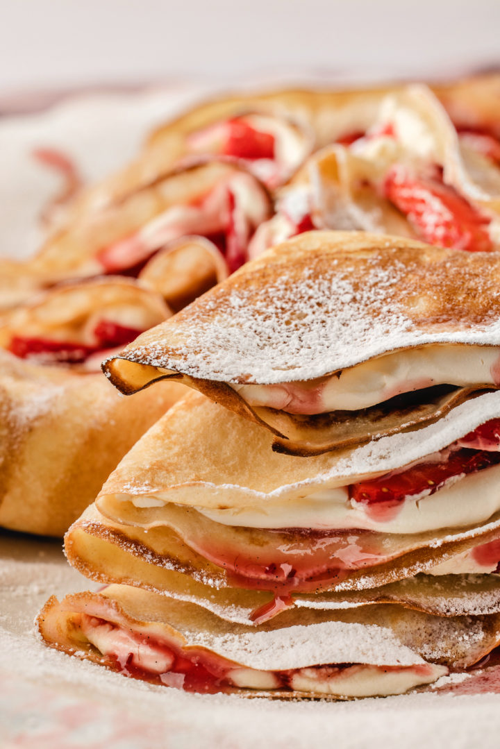 stack of crepes with strawberry filling dusted in powdered sugar