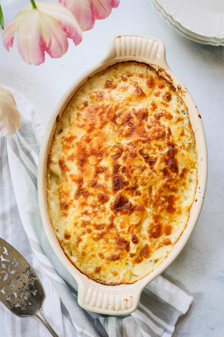 a casserole dish of baked cheesy scalloped potatoes on a wooden table