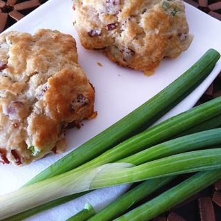 bacon and cheese scones on a white napkin with fresh green onions