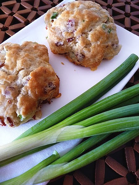 cheese and bacon scones on a white napkin with fresh green onions