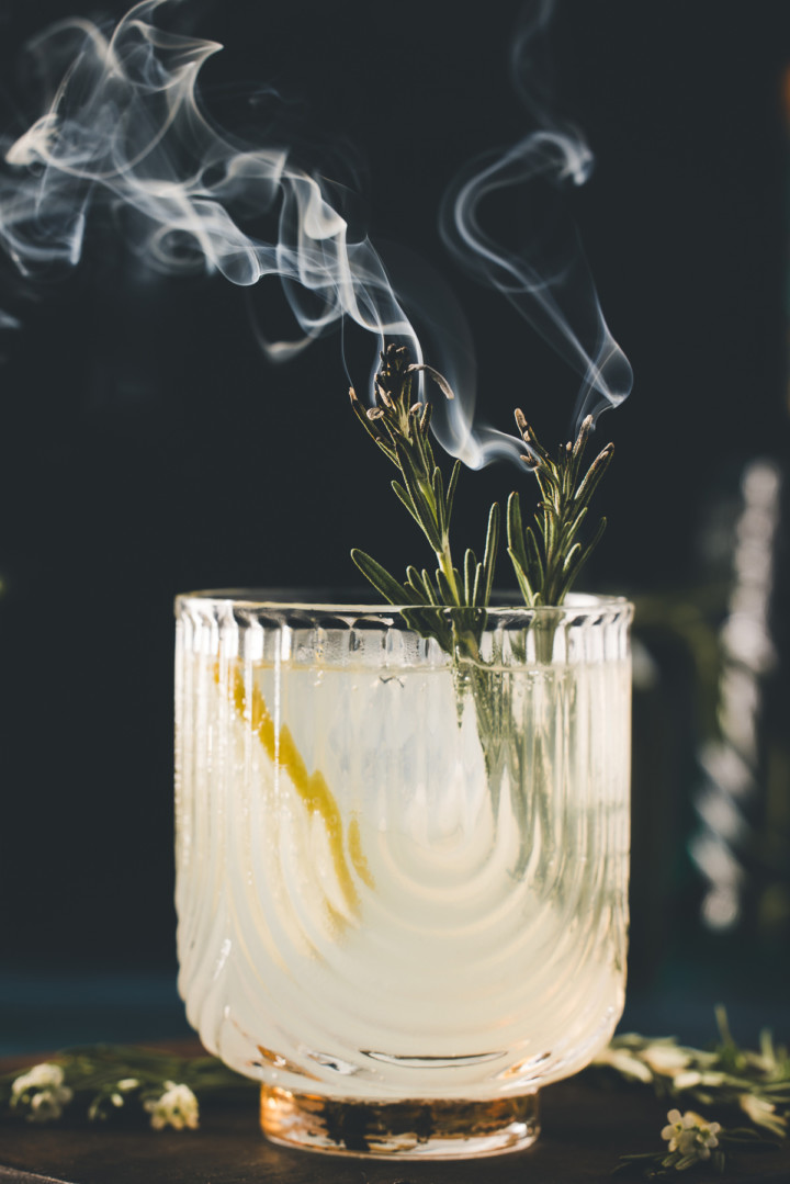 close up of burning rosemary garnish on a gin fizz cocktail