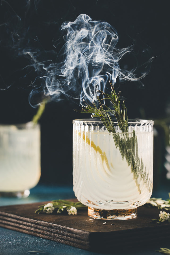 recipe for rosemary gin fizz garnished with smoking fresh rosemary