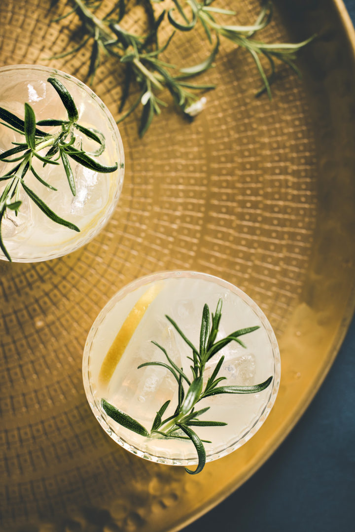 two glasses of gin with lemon cocktail on a gold tray