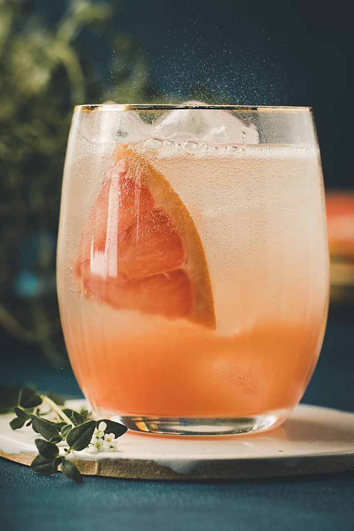 close up of a grapefruit slice in a glass of a gin and grapefruit juice cocktail