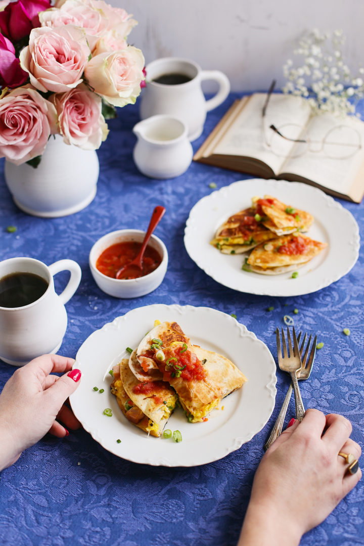 woman sitting at a table with a plate of easy breakfast quesadilla