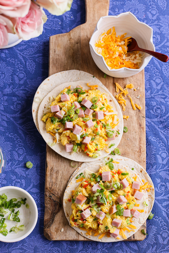 breakfast quesadillas being made with eggs, ham, onion, and peppers