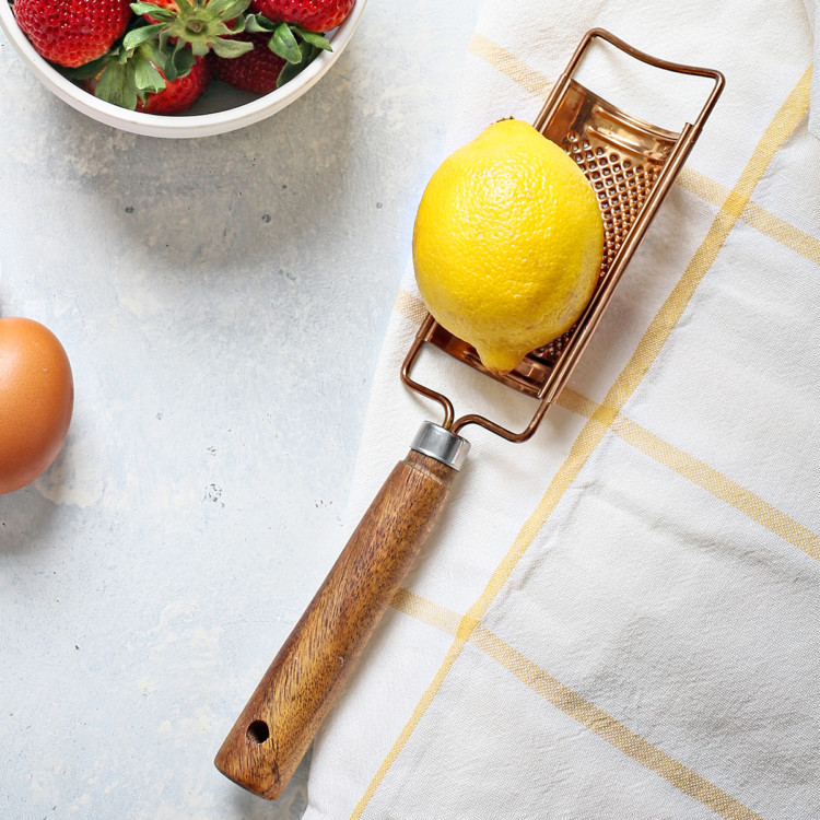 whole lemon with a lemon zester with wooden handle