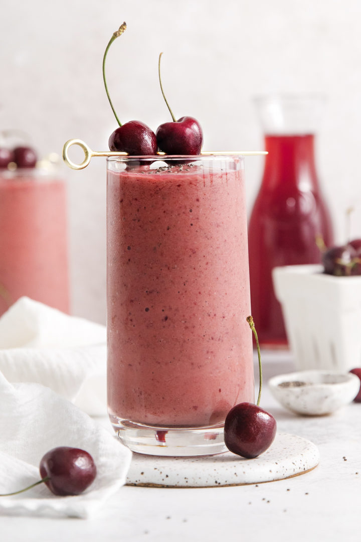 two glasses of mango cherry smoothie garnished with fresh cherries