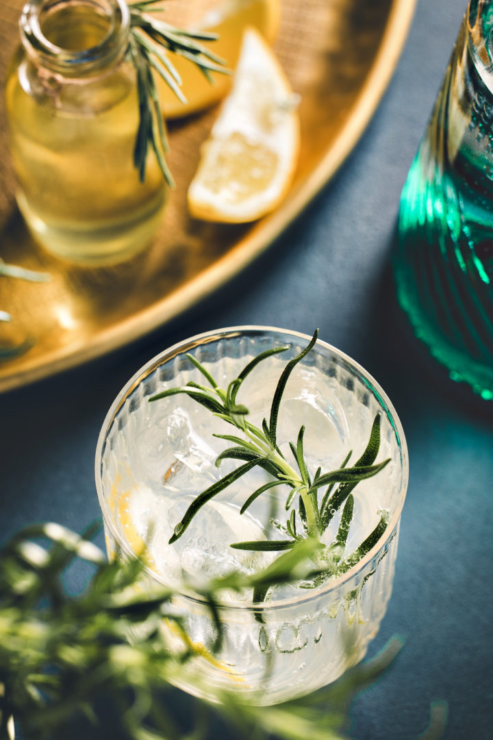 a glass with gin fizz next to a gold tray