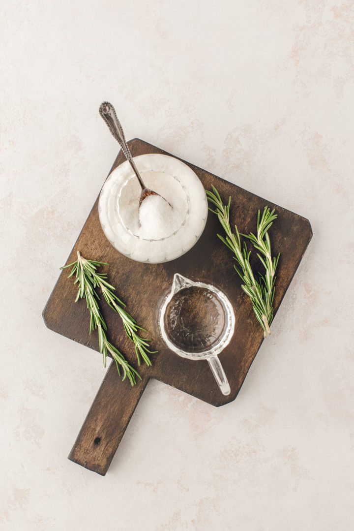 ingredients arranged on a wooden cutting board to make a rosemary simple syrup recipe