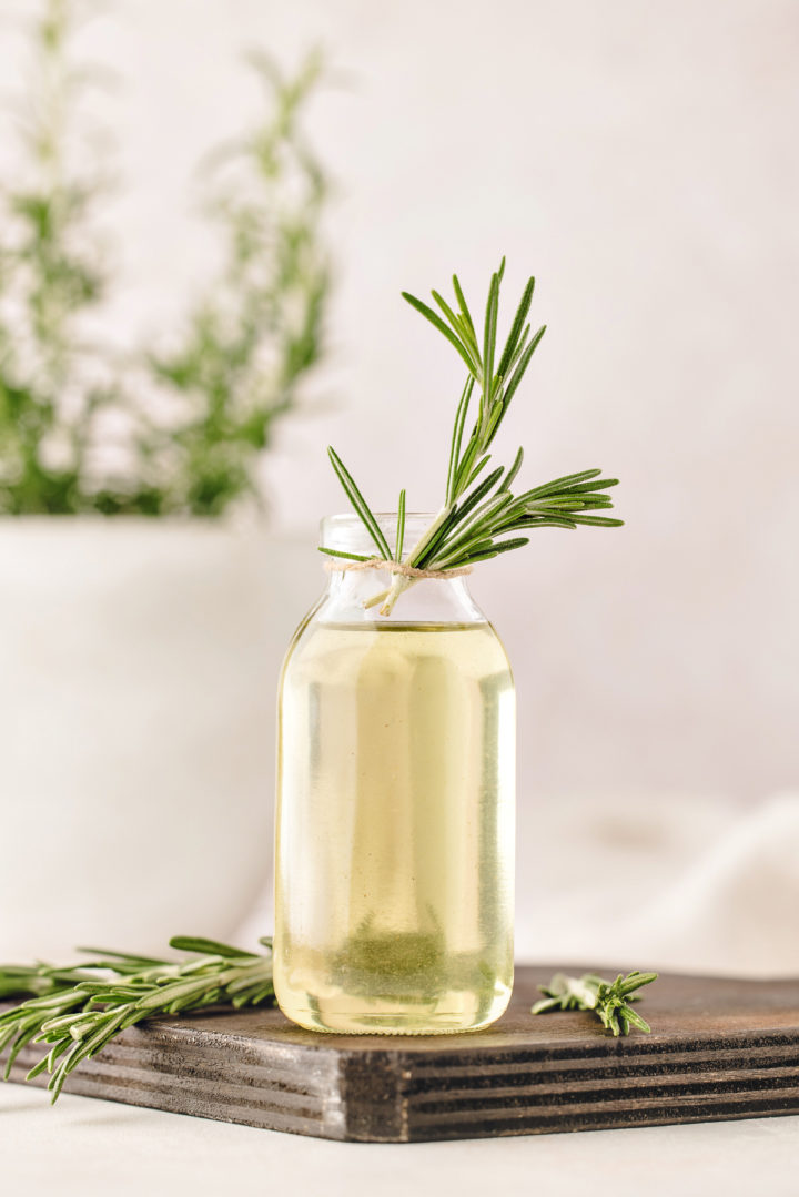 rosemary infused simple syrup in a glass bottle with a fresh rosemary garnish