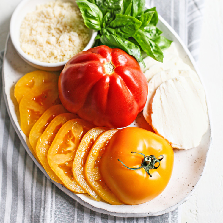 fresh yellow and red tomatoes on a white platter