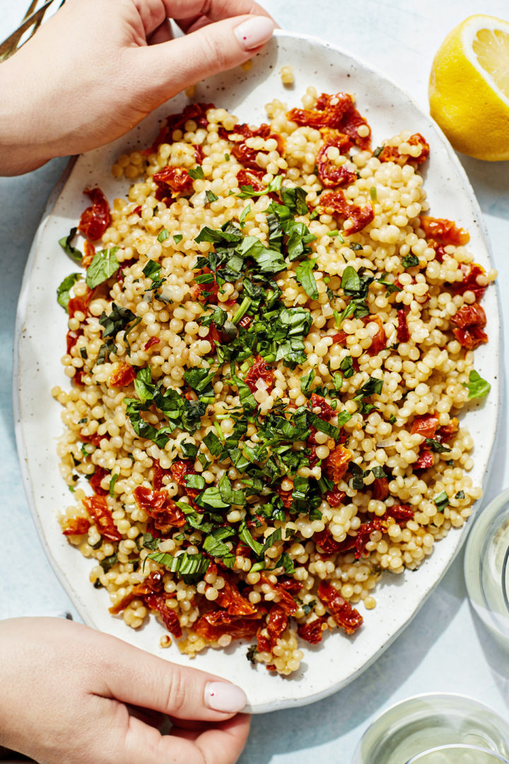 woman setting a table with pearled couscous salad
