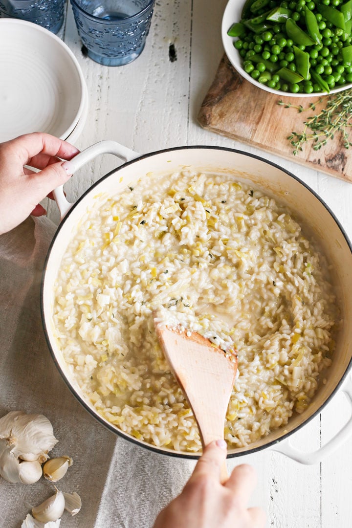 woman stirring a pan of creamy risotto