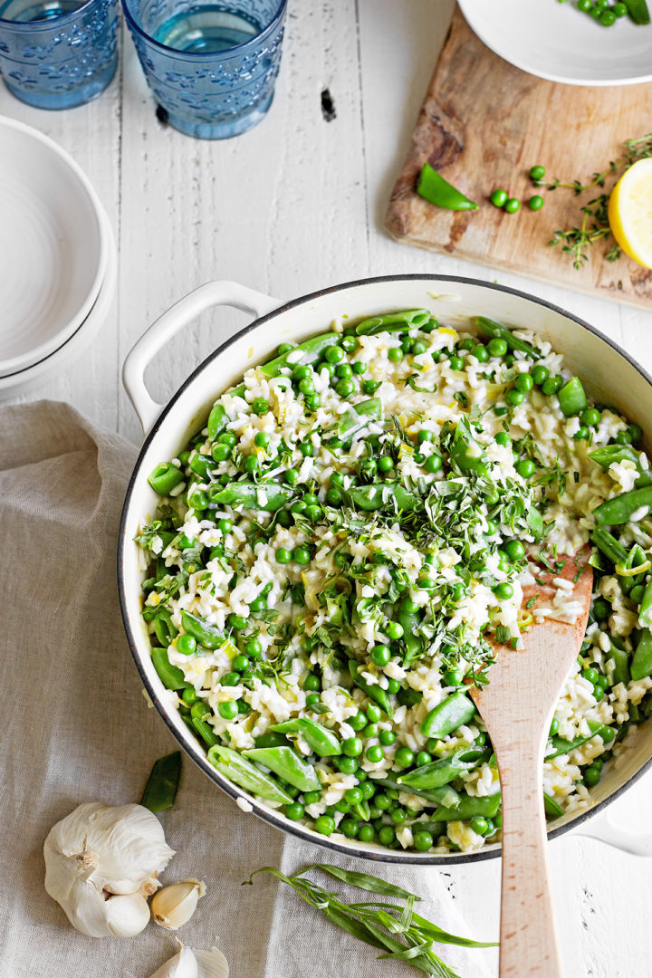 homemade risotto with peas in a pan with wooden spoon
