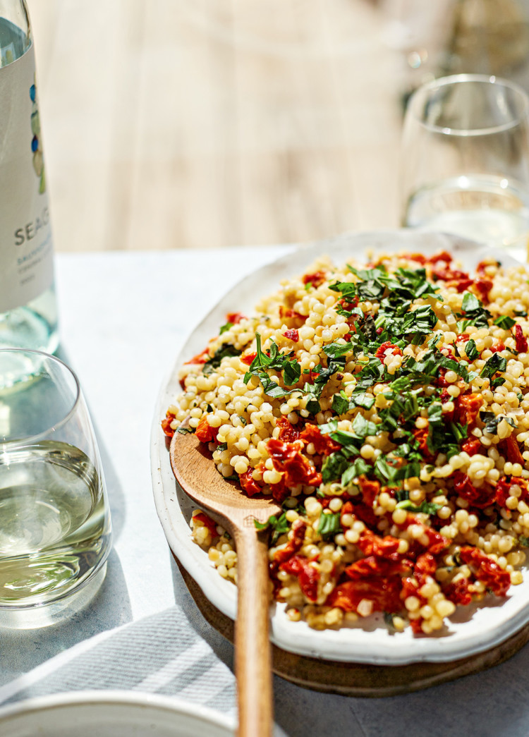 summer couscous salad on a platter with wooden spoon