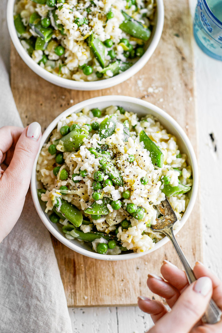 woman eating a bowl of risotto with spring vegetables
