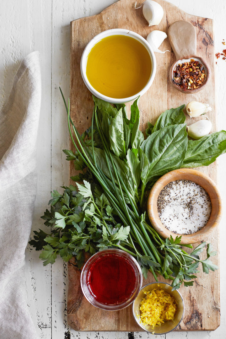 ingredients needed to make chimichurri skirt steak marinade arranged on a wooden board