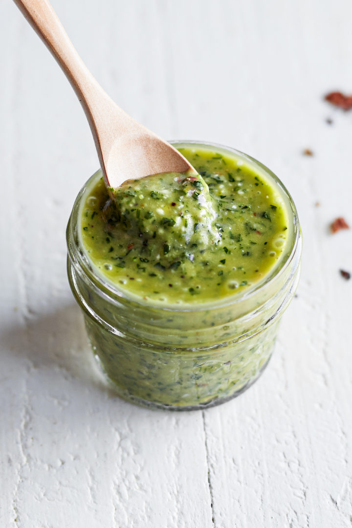 chimichurri skirt steak marinade in a glass jar with a wooden spoon