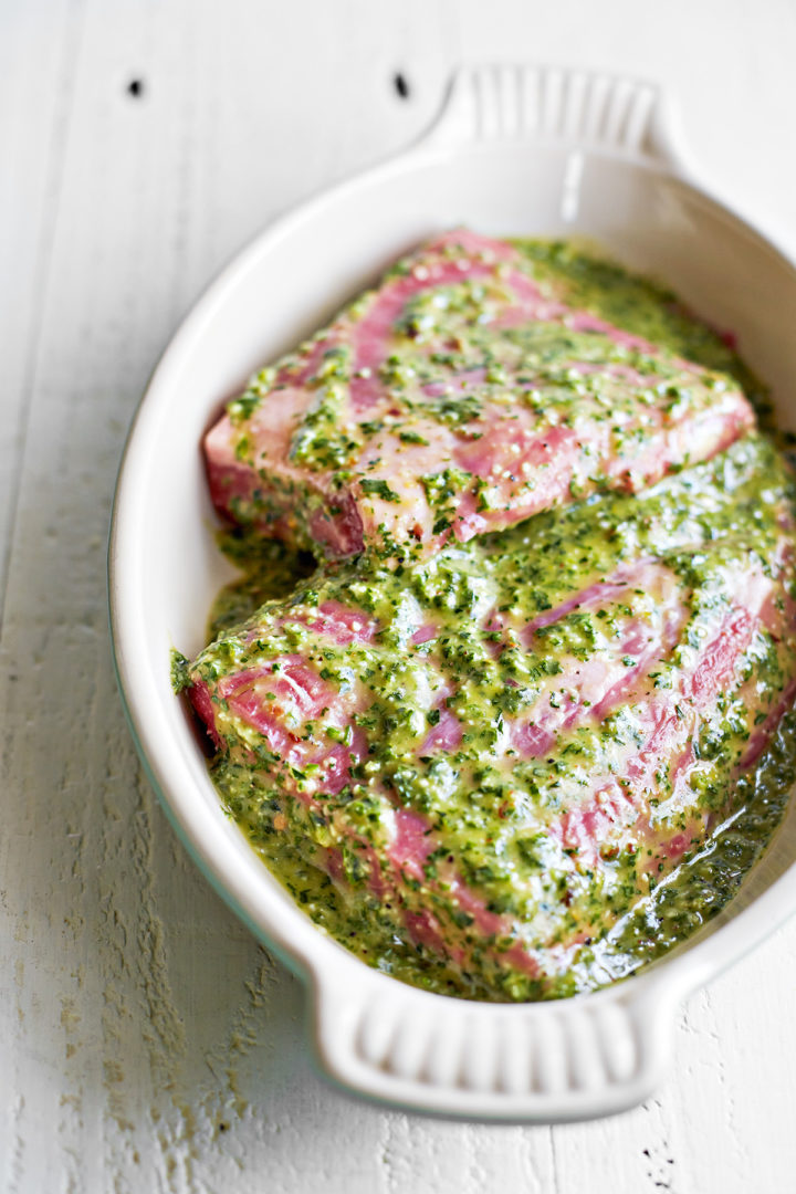 skirt steak with chimichurri sauce marinating in a dish