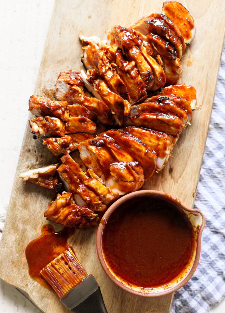 sliced grilled bbq chicken on a wooden cutting board
