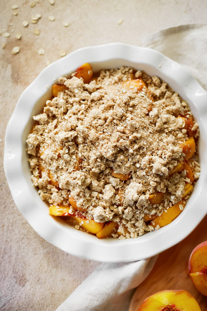 peach crisp with oatmeal in a baking dish before going into the oven