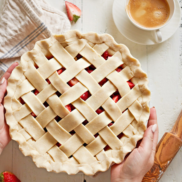 woman holding a pie with a lattice pie crust