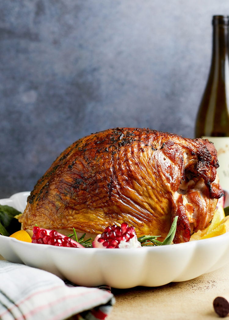 roasted turkey on a serving platter surrounded by citrus and pomegranate