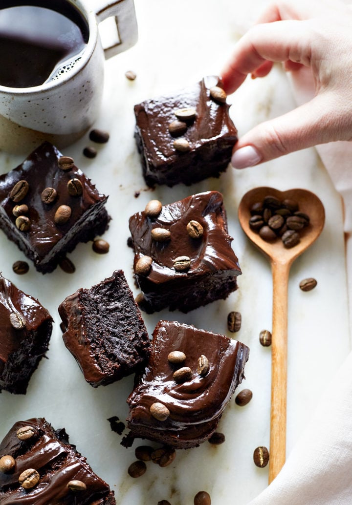 woman picking up an espresso brownie of a marble counter