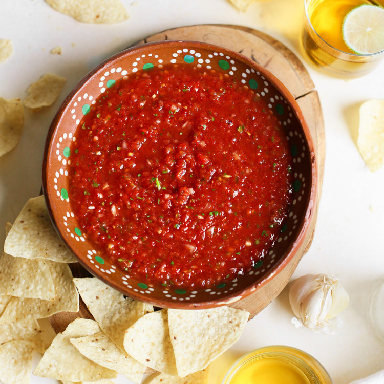 overhead photo of a bowl of salsa surrounded by tortilla chips and glasses of beer