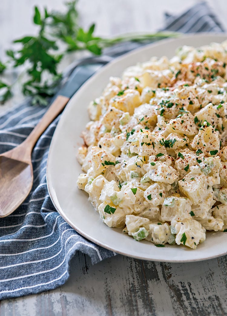 platter of potato salad next to a serving spoon