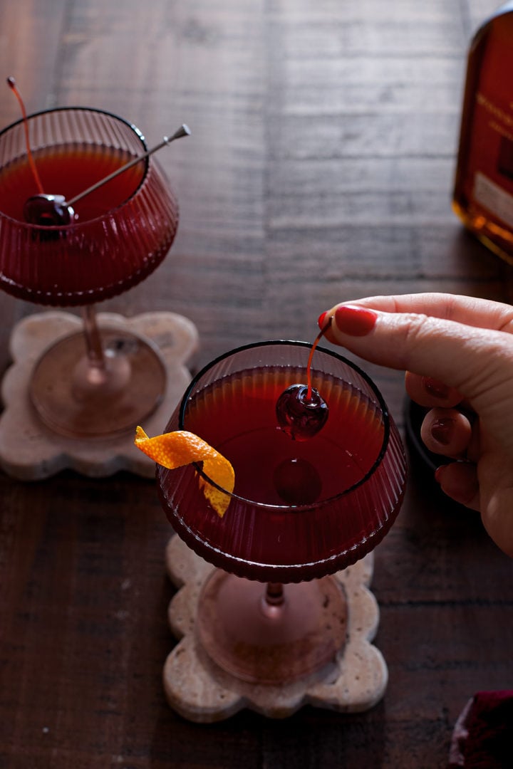 Garnishing a Christmas Manhattan with a cherry. 