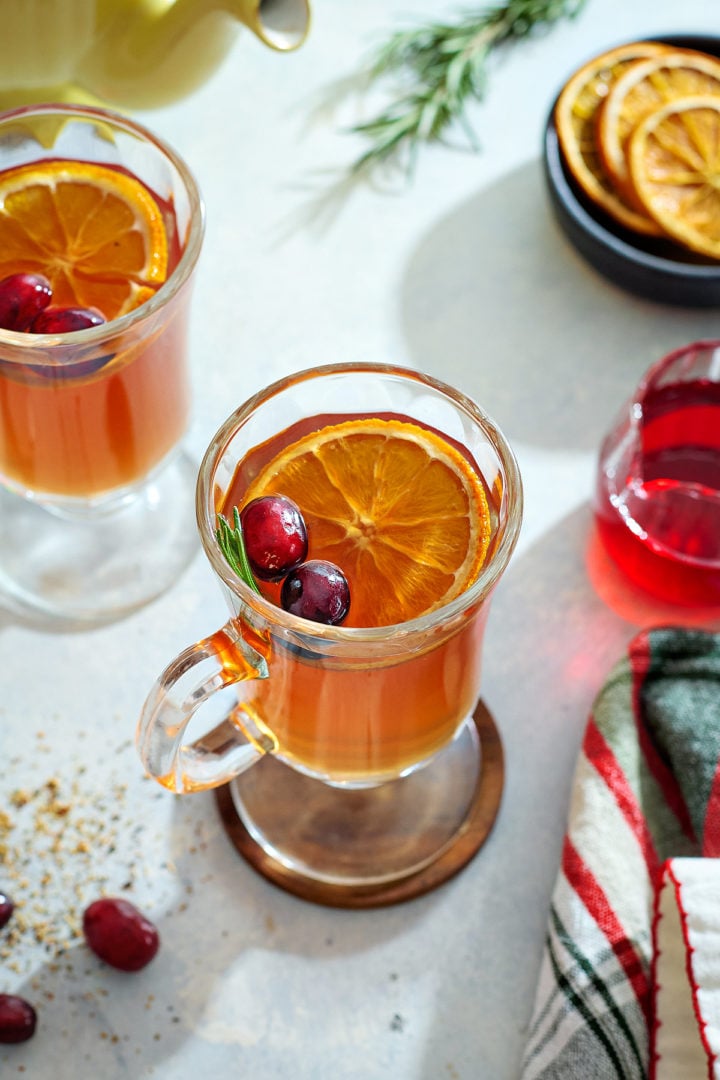 A cranberry hot toddy in a glass mug.