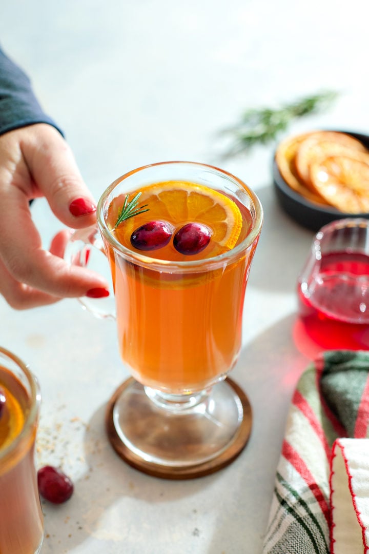 A woman's hand reaching for a whiskey and tea hot toddy.