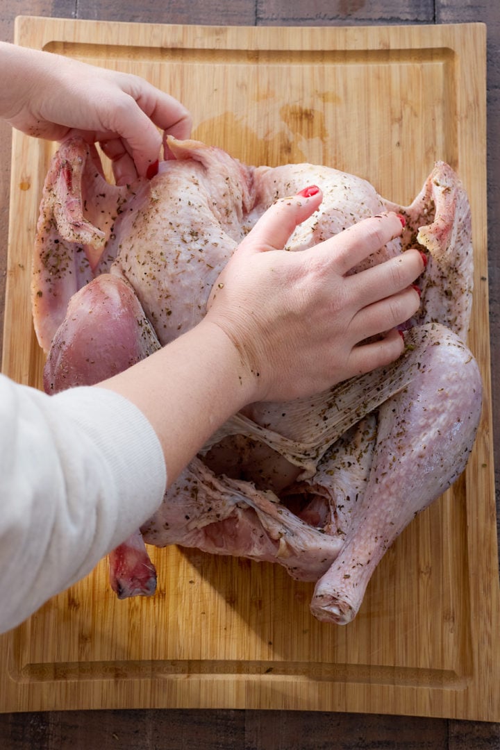 Pressing down on a turkey to flatten the breast bone.