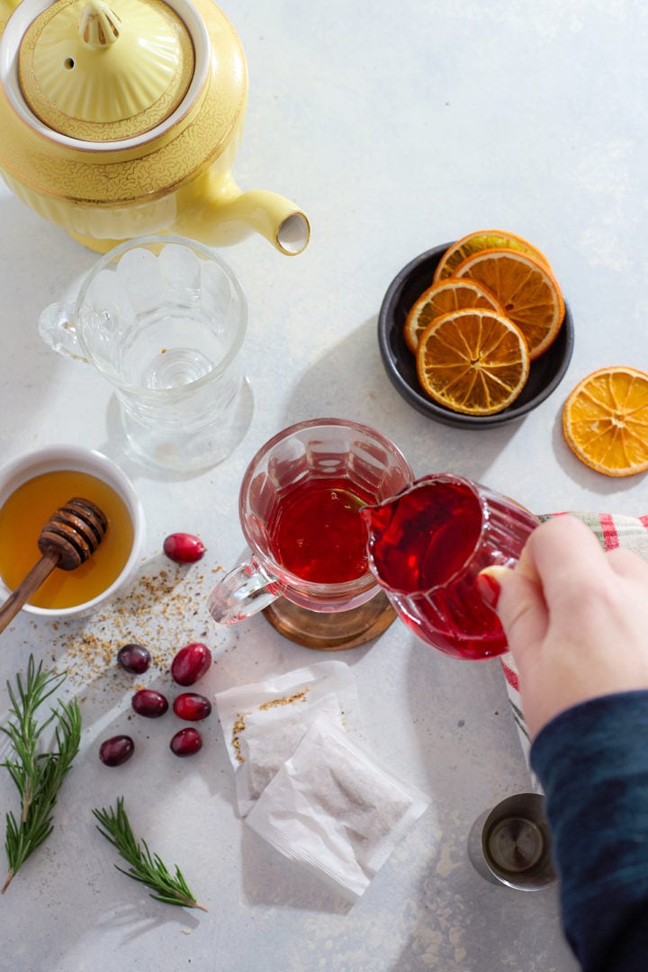 Adding cranberry syrup to a hot toddy.