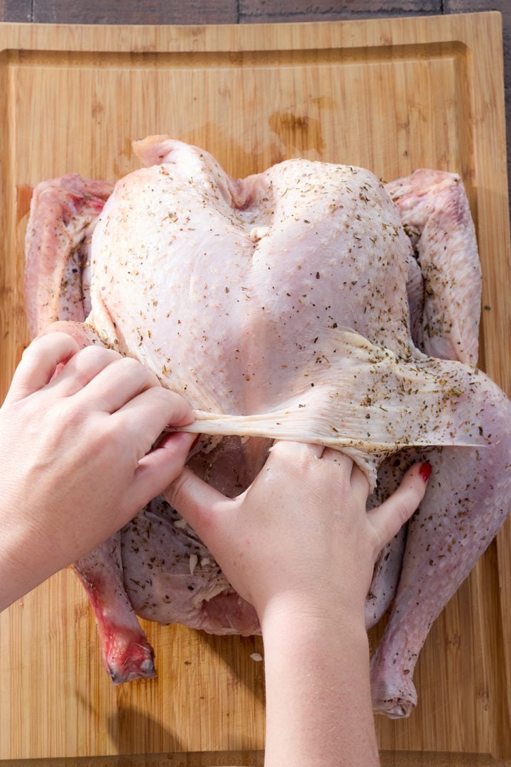 Pulling the turkey skin away from the meat to rub butter under it.